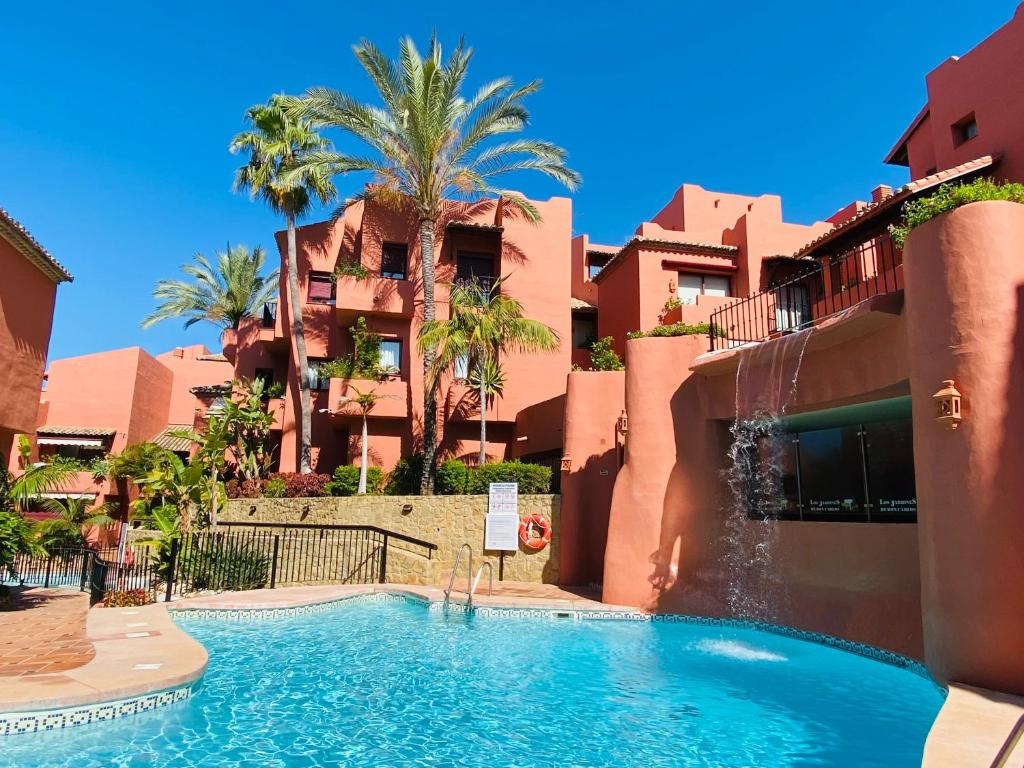 una piscina di fronte a un edificio con palme di Two-room apartment in Elviria NEAR THE BEACH with parking a Marbella