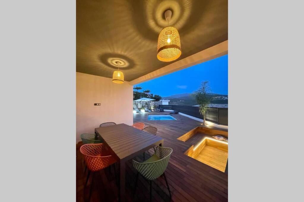 Cette maison dispose d'une terrasse avec une table en bois et une vue. dans l'établissement Villa moderne avec Piscine - Porticcio, à Grosseto-Prugna