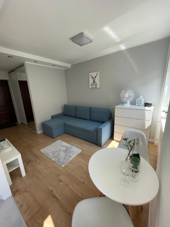 uma sala de estar com uma mesa e um sofá azul em Chill Apartament Gdynia em Gdynia