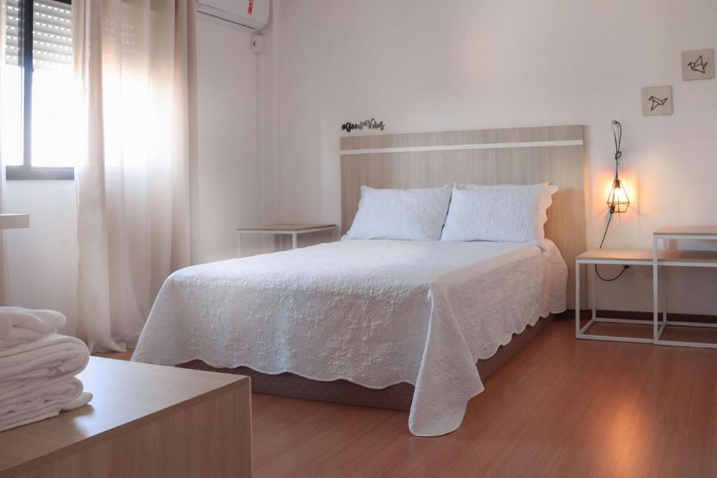 Dormitorio blanco con cama con sábanas y almohadas blancas en Belo Apartamento Central Master Collection en Passo Fundo