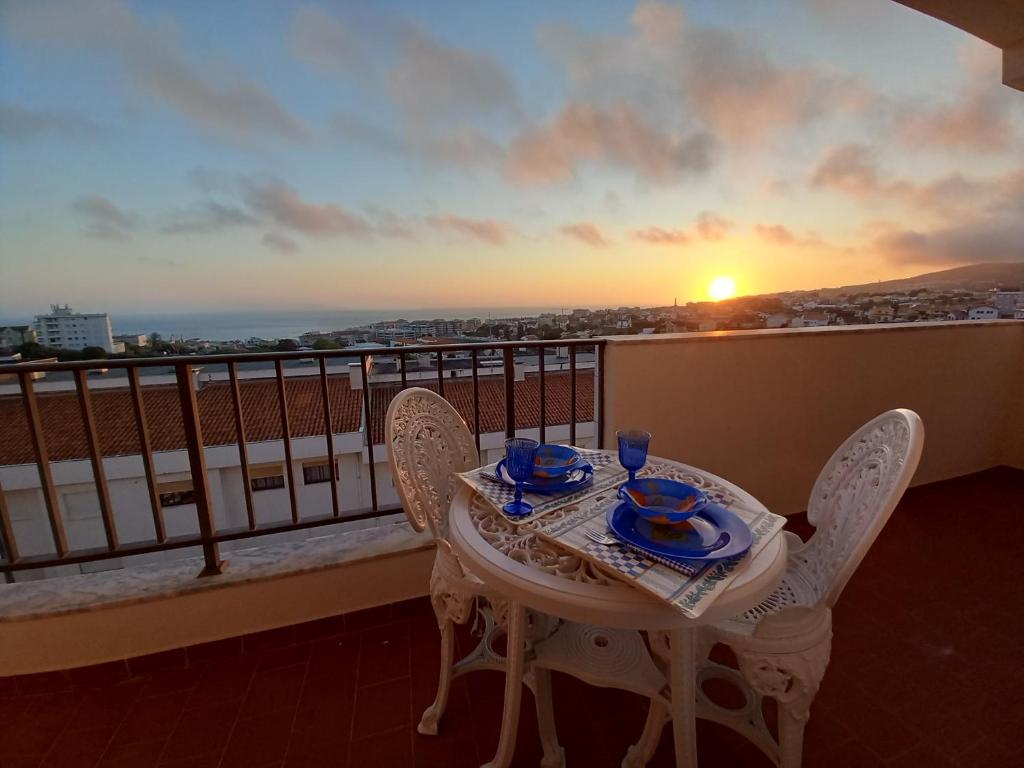 a table and chairs on a balcony with the sunset at Figueira House AL in Figueira da Foz