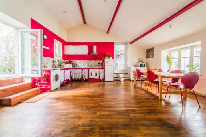 a large kitchen with red walls and a table and chairs at Appartement rouge avec jardin in Eymoutiers