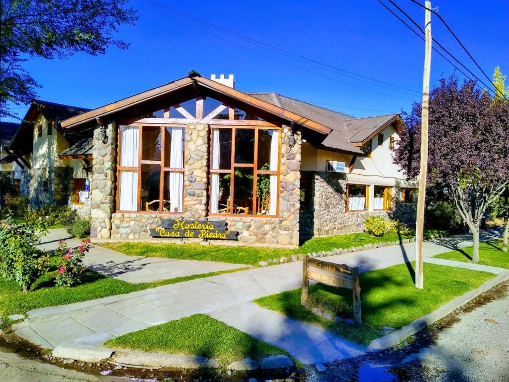 una casa con un banco delante de ella en Hosteria y Cabañas Casa de Piedra en Trevelín