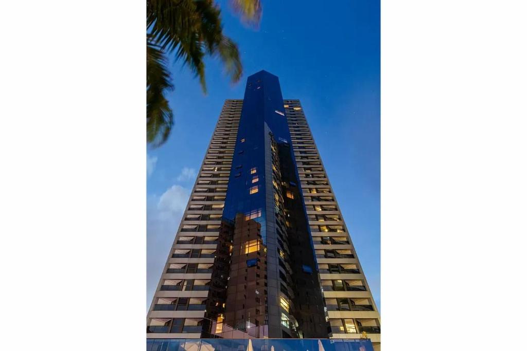 ein hohes blaues Gebäude mit einer Palme in der Unterkunft HY Beach Flats - International in Recife