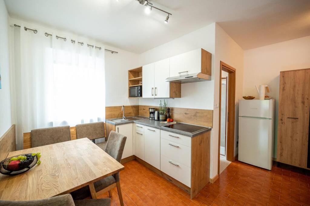 uma cozinha com uma mesa e um frigorífico branco em Ferienwohnung am Kalterer See in Südtirol em Caldaro
