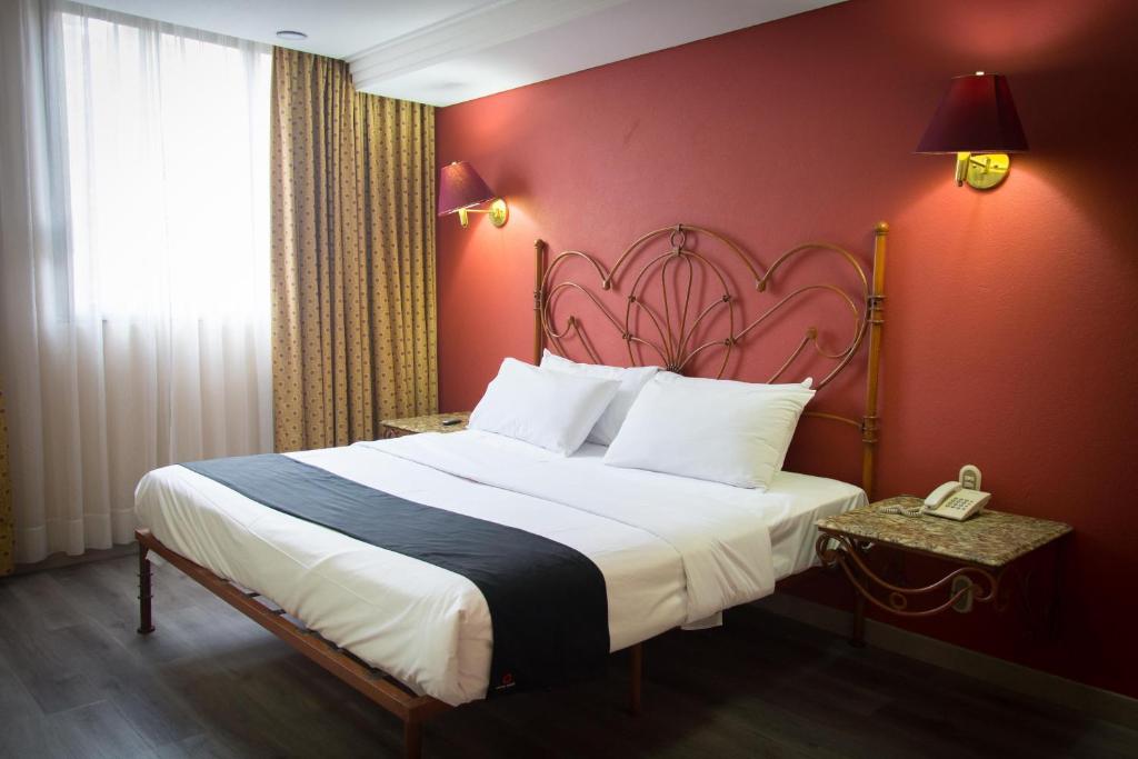 1 dormitorio con 1 cama grande y pared roja en Hotel Santa Maria, en Ciudad de México