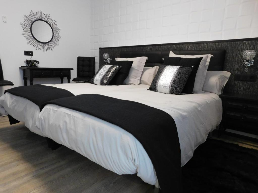 - un grand lit avec des oreillers en noir et blanc dans l'établissement HOTEL TERRA GALEGA MEIGA, à Monforte de Lemos