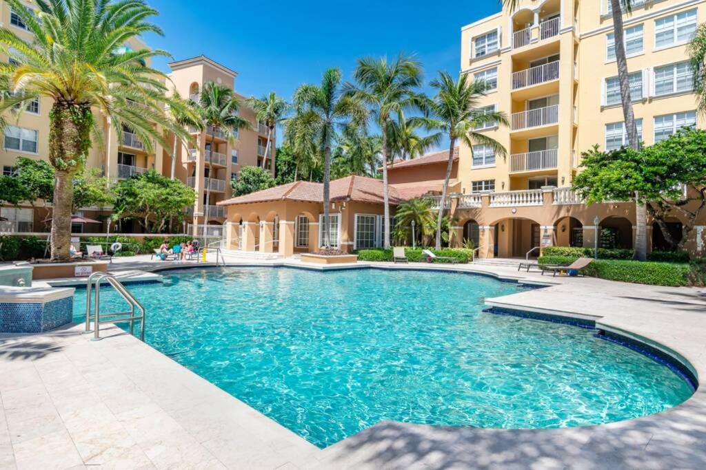 a swimming pool with palm trees and a building at Entire condo at Aventura in Aventura