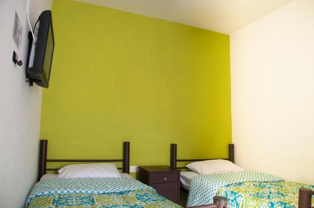 a room with two beds and a yellow wall at Hotel Bugambilias in Ciudad Obregón
