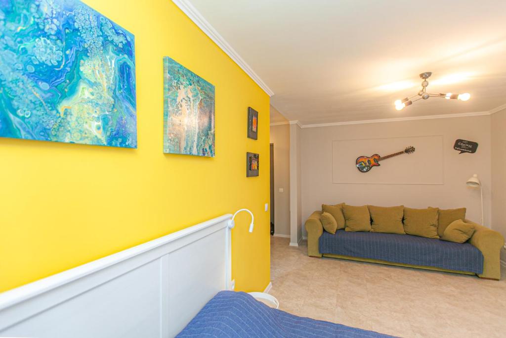 a living room with a couch and a yellow wall at City Jazz studio in Kaliningrad