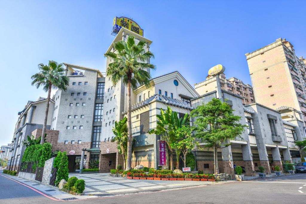 a building with palm trees in front of a street at Purple Garden Motel in Kaohsiung