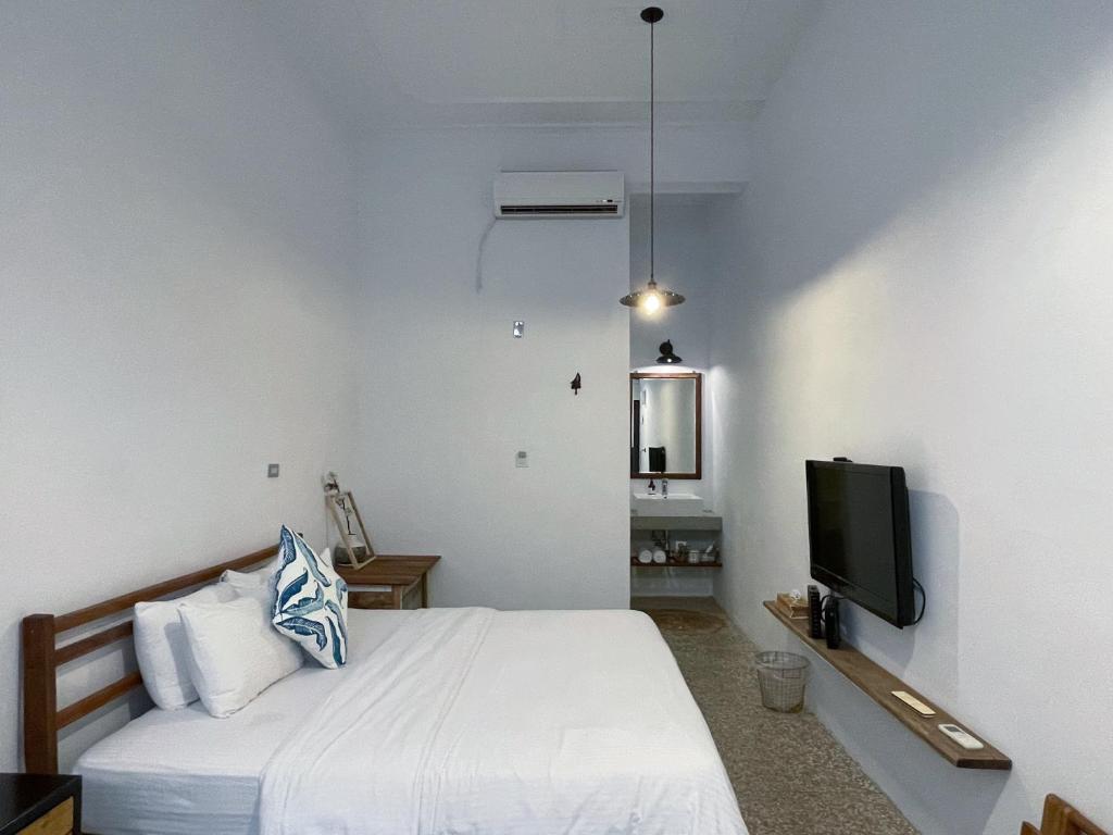 a white bedroom with a bed and a tv at 8 Door老宅民宿 in Hengchun