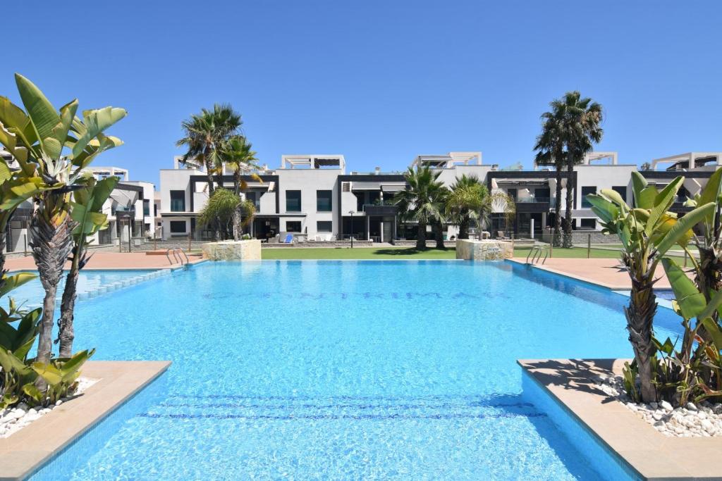 a large swimming pool with palm trees and buildings at Oasis Beach in Orihuela