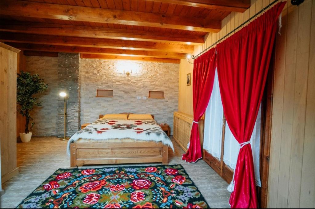 a bedroom with a bed with red curtains and a rug at Casa DAVIDEN in Moisei