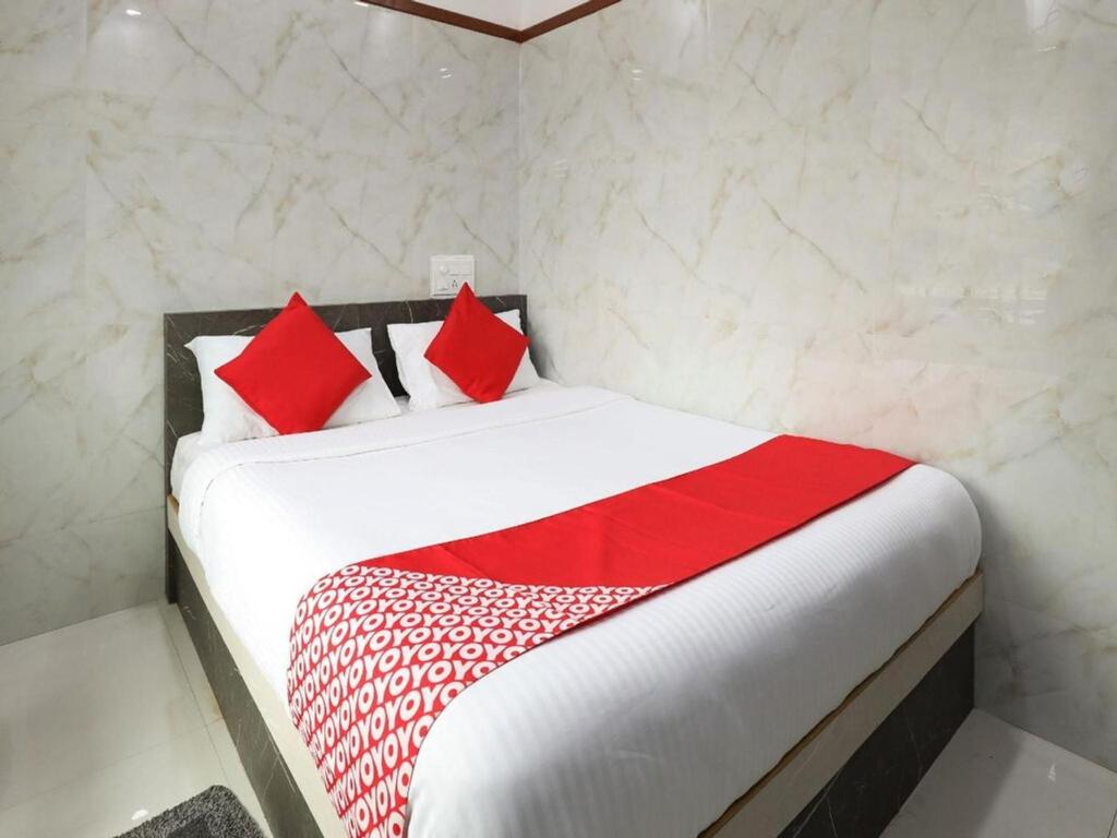 a white bed with red pillows in a room at Guru Comforts Belur in Belūr