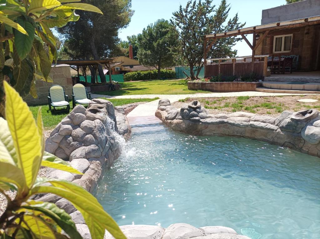 a pool in a yard with a rock retaining wall at Casa Mirlo in Montmesa