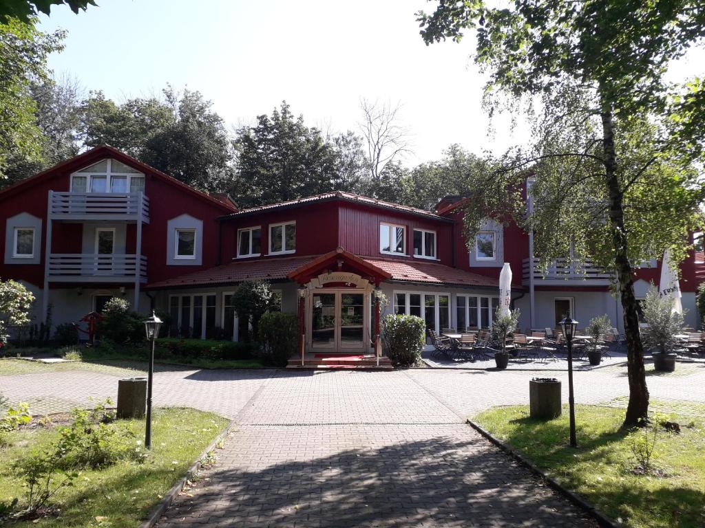 a red house with a tree in front of it at Hotel Rosengarten Leipzig-Naunhof in Naunhof