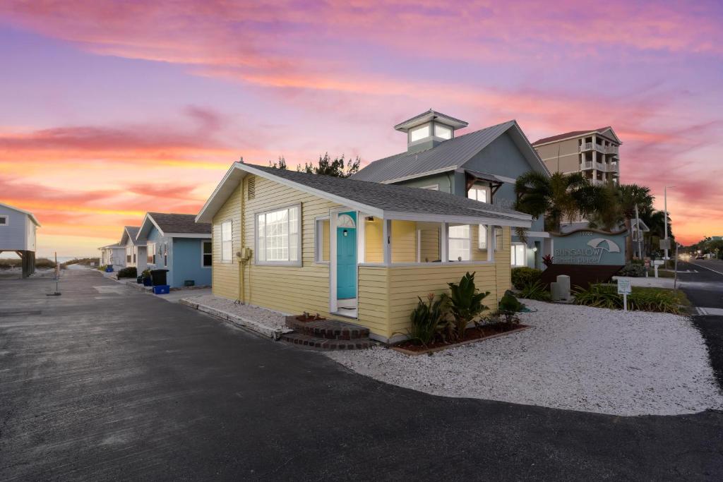 a yellow house on the beach with a sunset at Canary Beach Cottage in Clearwater Beach