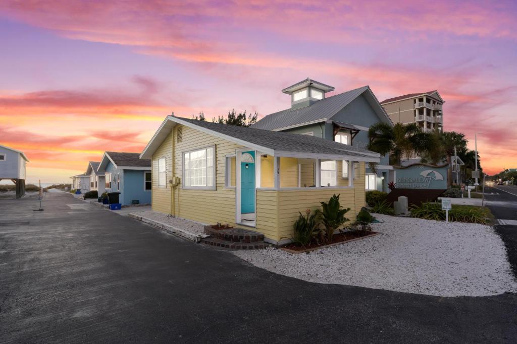 una casa amarilla en la playa con puesta de sol en Canary Beach Cottage, en Clearwater Beach