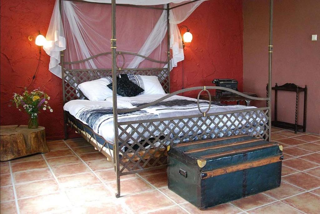 ein Schlafzimmer mit einem Himmelbett aus Metall und einem Kofferraum in der Unterkunft Gezinskamer van Waard van Kekerdom in Kekerdom