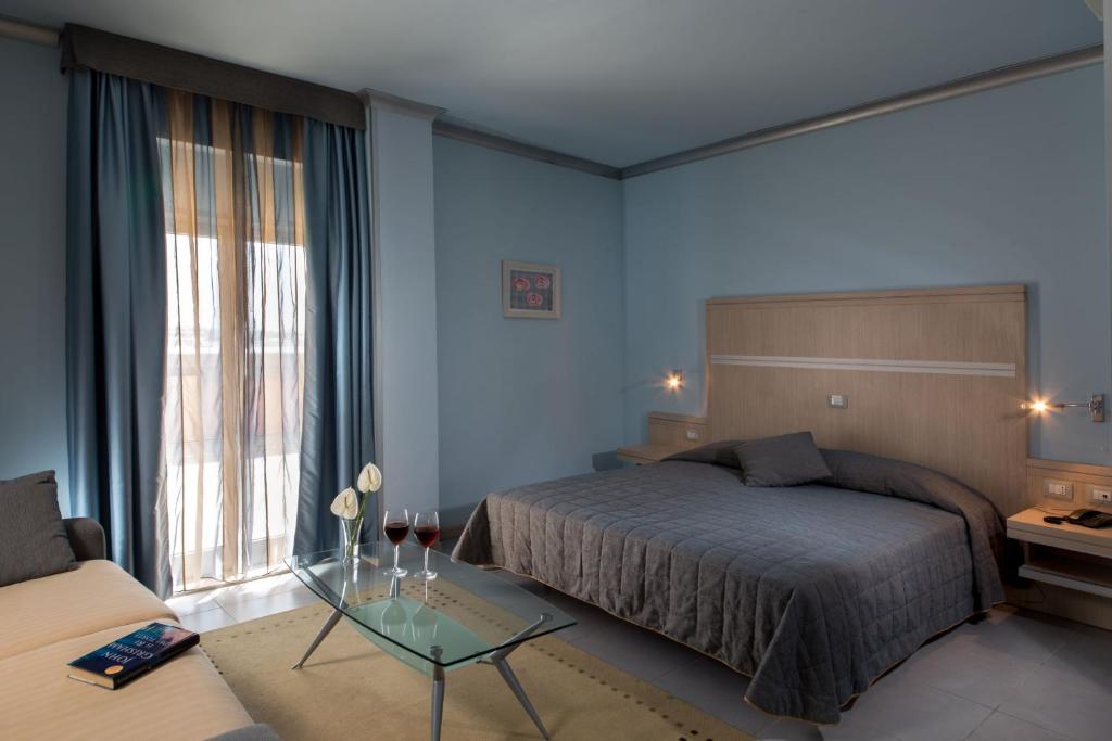 a bedroom with a bed and a table and a couch at Hotel Mediterraneo in Livorno
