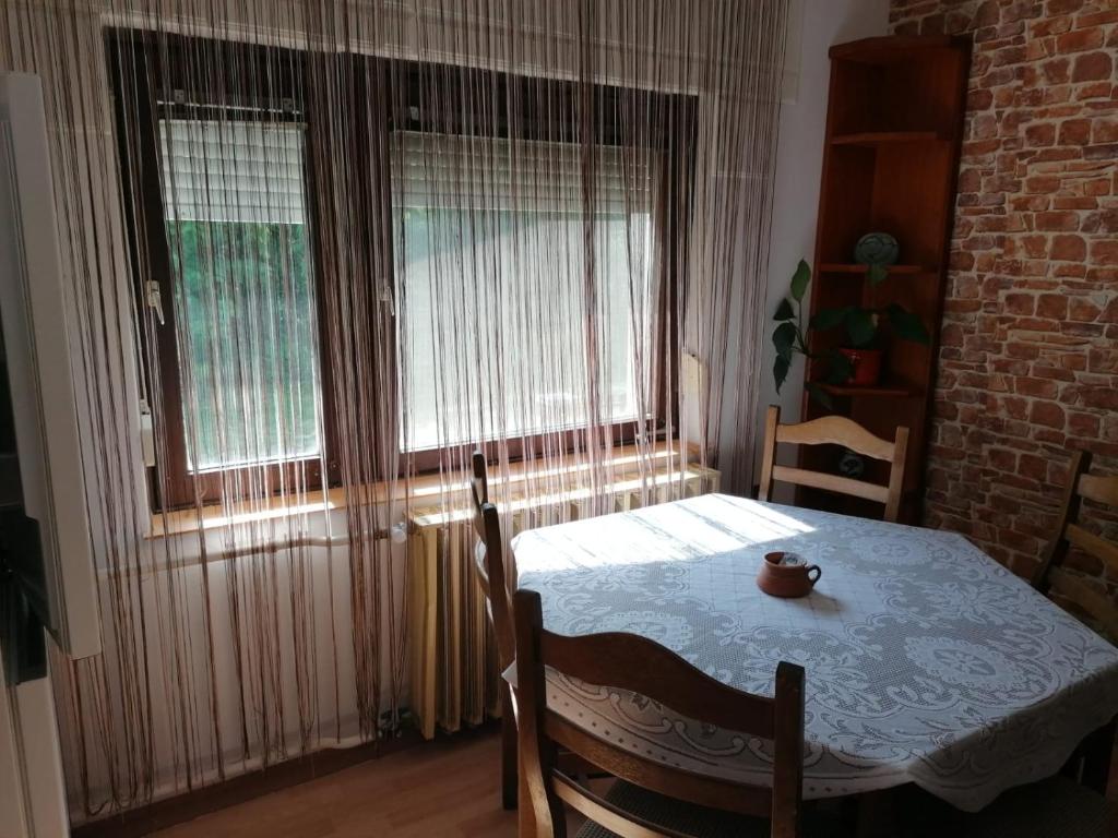 a dining room with a table and two windows at Pálinkás jó reggelt! in Hévíz