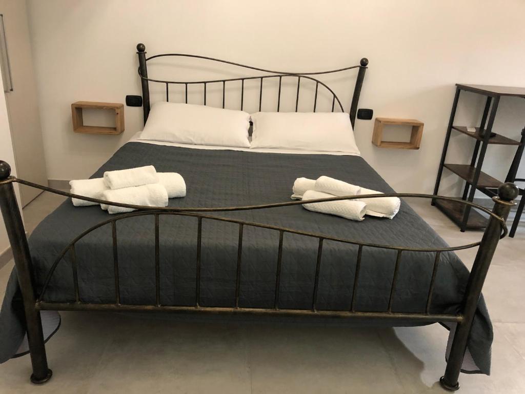Una cama negra con dos toallas blancas. en B&B Le Mura, en Iglesias