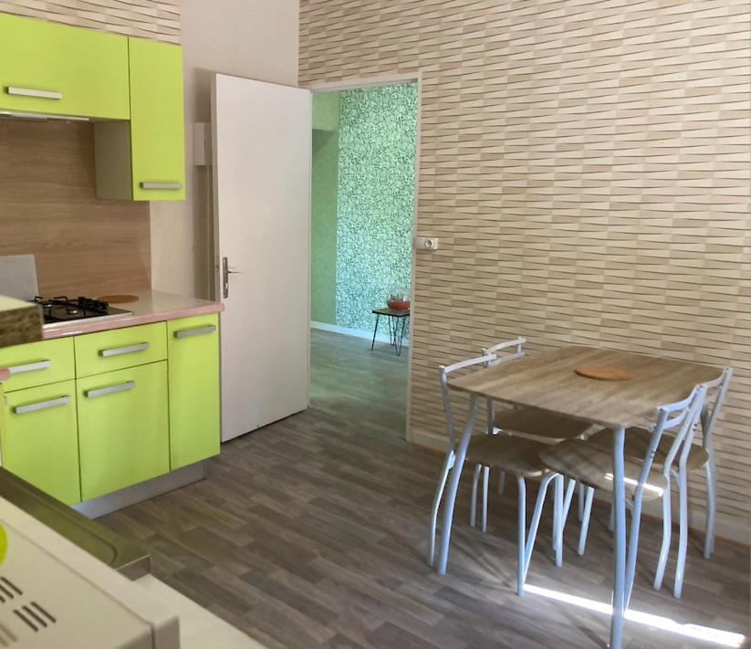 a kitchen with green cabinets and a table with chairs at Appartement La Libellule, professionnels et vacanciers in Compreignac