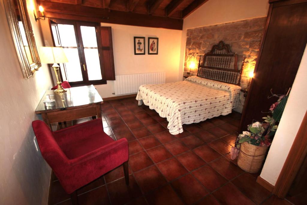 a bedroom with a bed and a red chair at Casa Rural El Meson in Briones