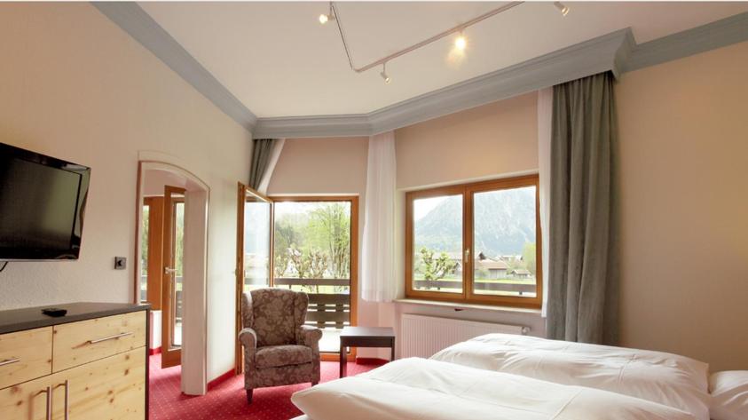 1 dormitorio con 1 cama, TV y silla en Wittelsbacher Hof, en Oberstdorf
