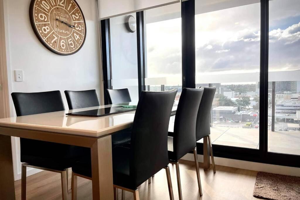 mesa de comedor con sillas y reloj en la pared en Enjoy a little Luxury in Adelaide CBD - Perfect! en Adelaida