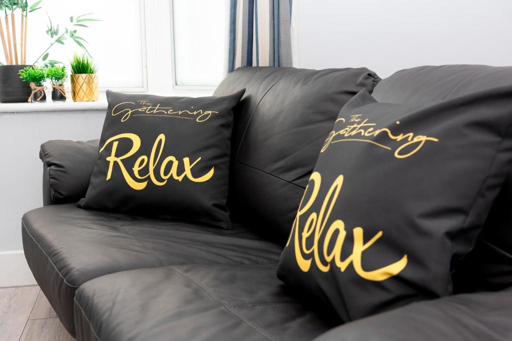 two black pillows with the words relax on a couch at Wrexham Central Stay - Apartment Six in Wrexham