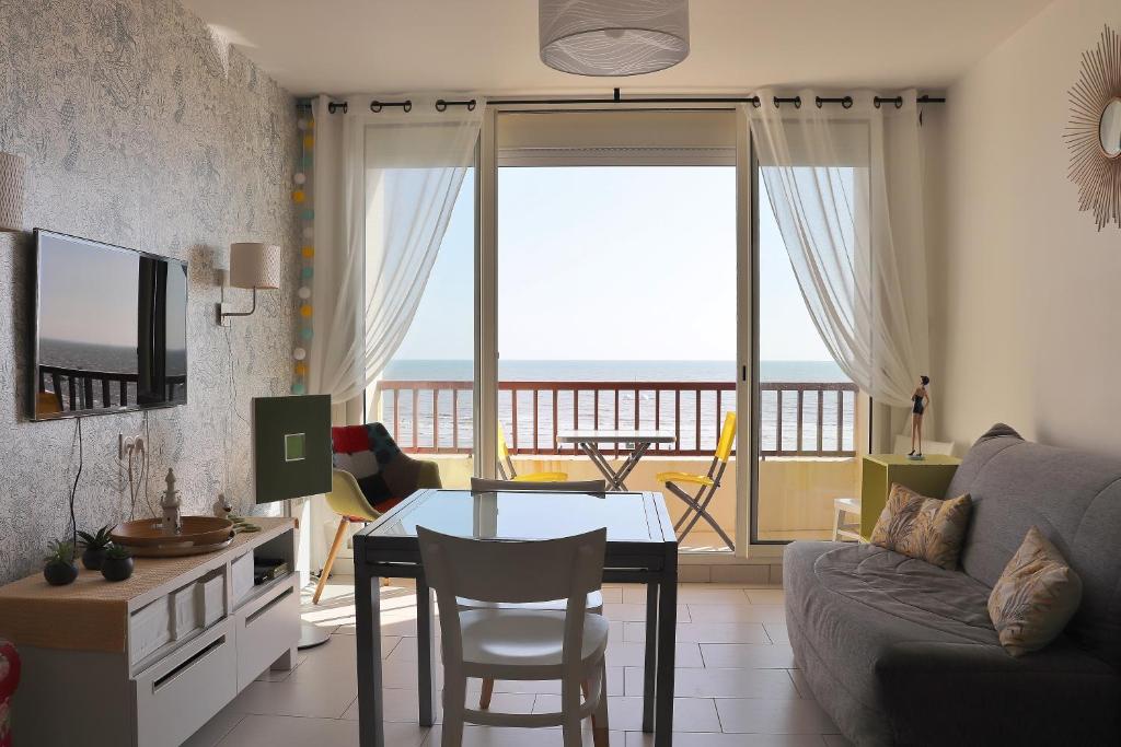 een woonkamer met een tafel en uitzicht op de oceaan bij Studio Front de Mer in Saint-Jean-de-Monts