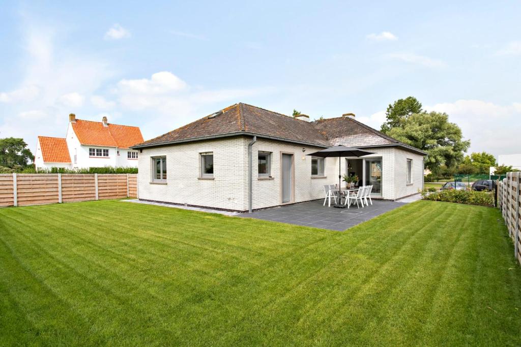 
a large white house sitting in a grassy area at Bright and spacious bungalow with garden near the beach in Middelkerke
