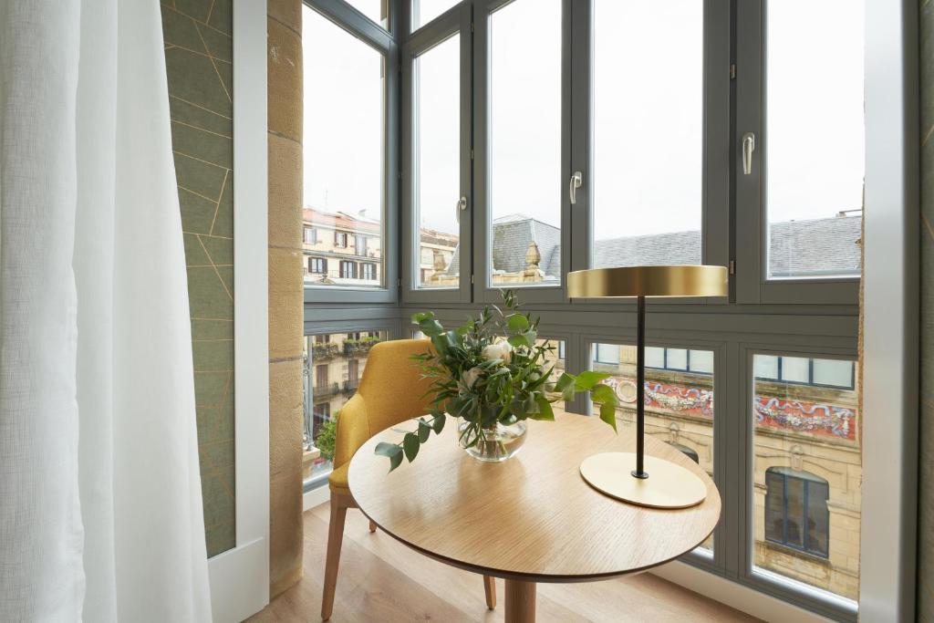 uma mesa com flores e um candeeiro num quarto com janelas em Intelier Villa Katalina em San Sebastián