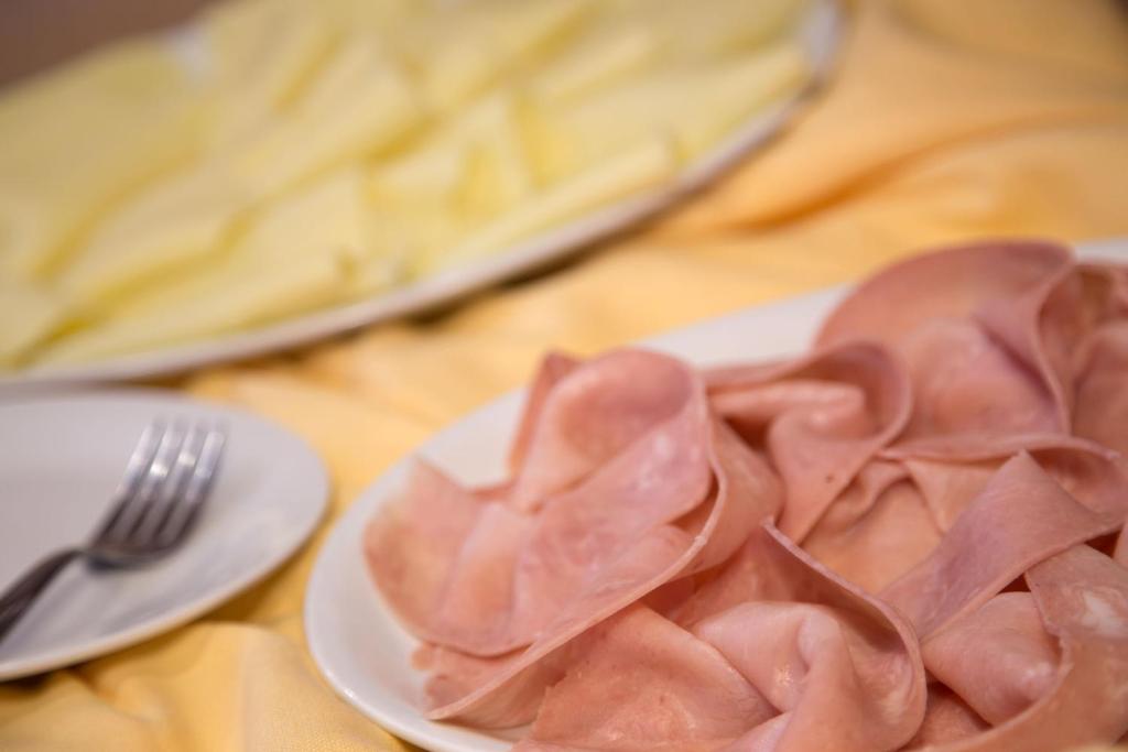 a plate of ham on a table with a fork at Hotel Mediterraneo in Livorno