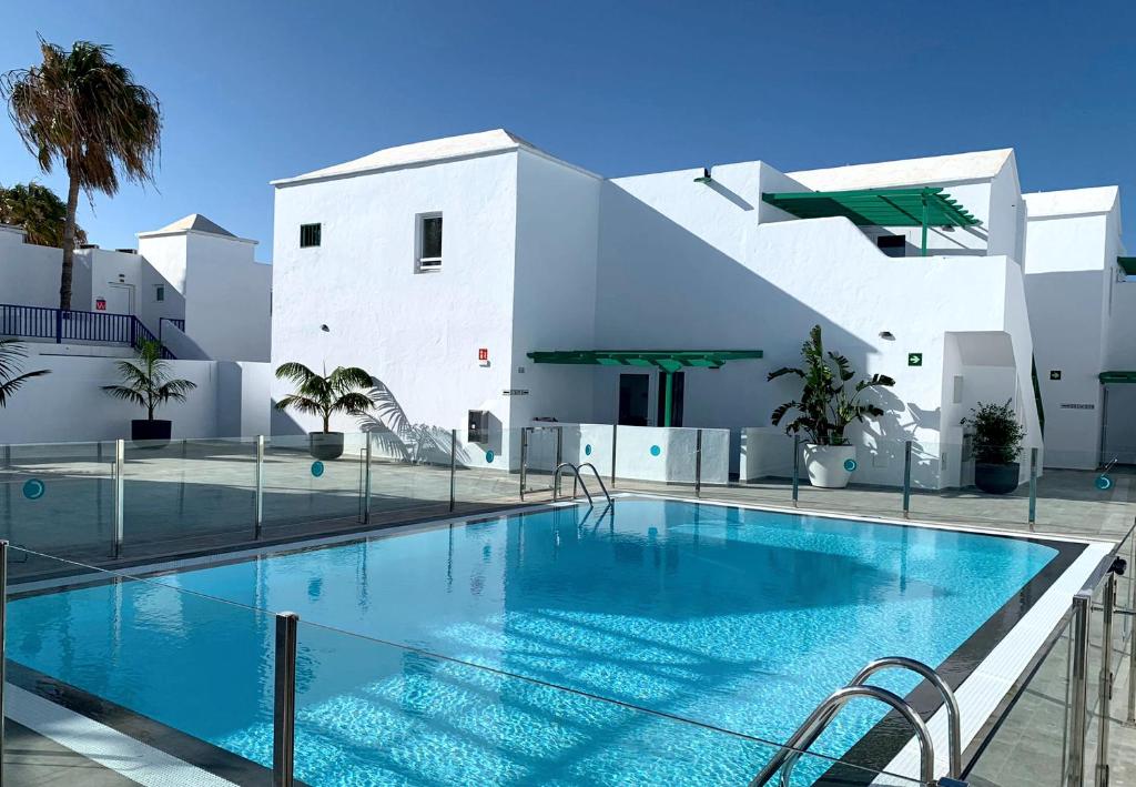 a swimming pool in front of a white building at Apartamentos Celeste in Costa Teguise