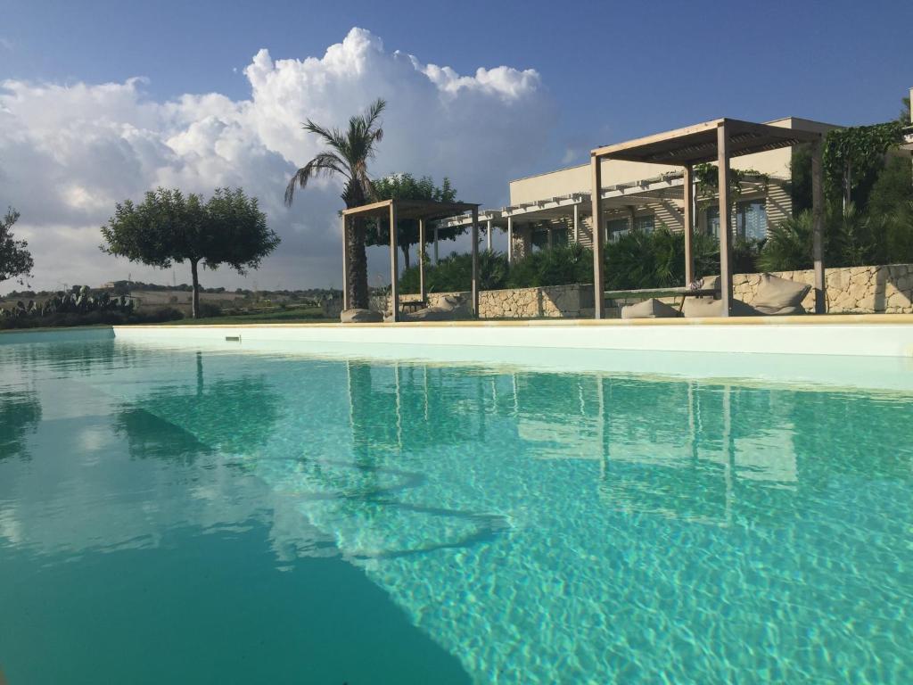 uma grande piscina de água azul em frente a um edifício em Scilla Maris Charming Suites em Marzamemi