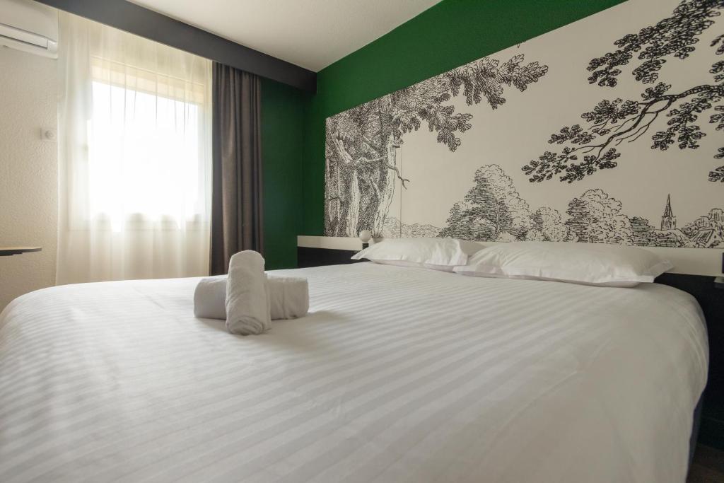 a bedroom with a large white bed with green walls at The Originals City Hôtel Bordeaux Porte du Bassin in Gradignan