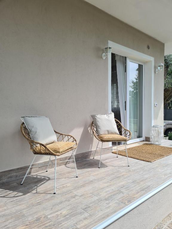 dwa krzesła siedzące na patio z oknem w obiekcie Sofia's Cottage w mieście Sommacampagna