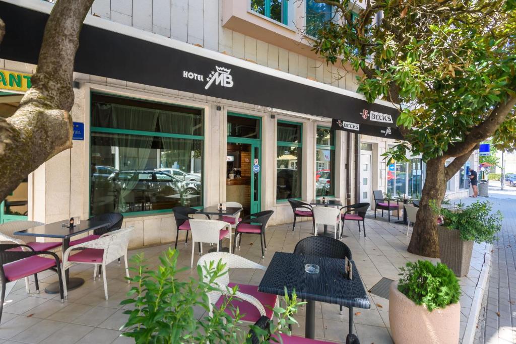 un café avec des tables et des chaises en face d'un bâtiment dans l'établissement Hotel MB, à Metković