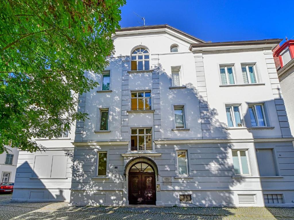 un grand bâtiment blanc avec un arbre devant dans l'établissement The Cozy Lindau No 1, à Lindau