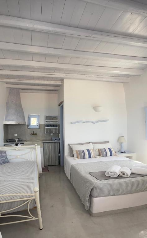 a white bedroom with two beds and a kitchen at Palio Karnagio Παλιό Καρνάγιο in Koufonisia