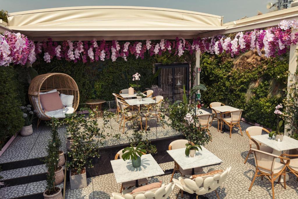 un patio esterno con tavoli, sedie e fiori di ODSweet Duomo Milano Hotel a Milano