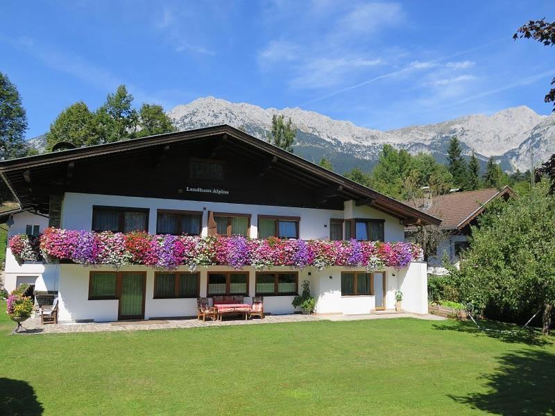 a house with flowers on the side of it at Landhaus Alpina in Scheffau am Wilden Kaiser