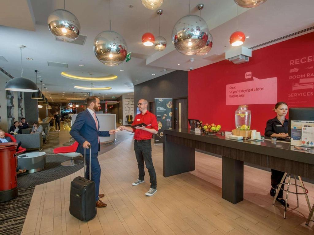 two men standing in a lobby with a counter at ibis London Blackfriars in London