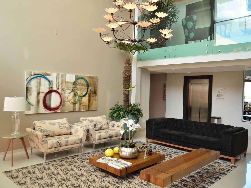 a living room with a black couch and a table at Hotel Matão By Mercure in Matão