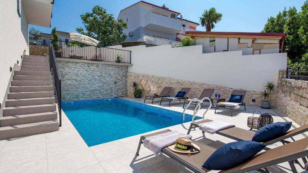 a swimming pool in a yard with chairs and a building at Apartments Villa Frankola with swimming pool in Crikvenica