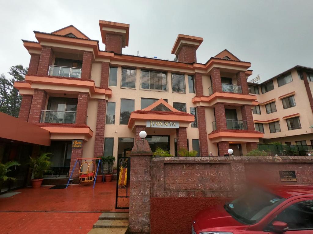 a building with a red car parked in front of it at Jivanta Mahabaleshwar in Mahabaleshwar