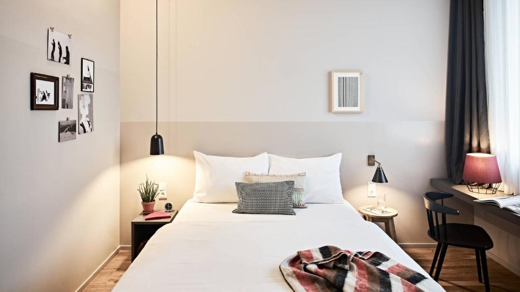 a bedroom with a large white bed with a desk at Bold Hotel München Giesing in Munich